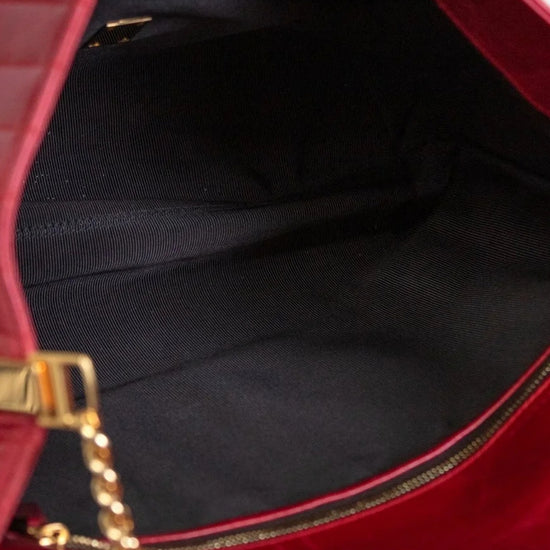 Close-up of a red handbag with gold chain detail on a black interior.