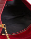 Close-up of a red handbag with gold chain detail on a black interior.