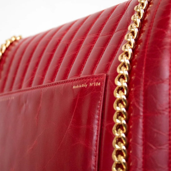 Red handbag with gold chain strap on a white background