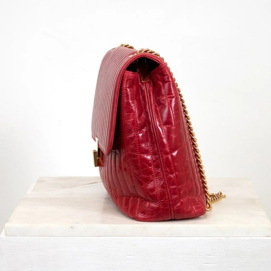 Red textured handbag with gold chain on a white background