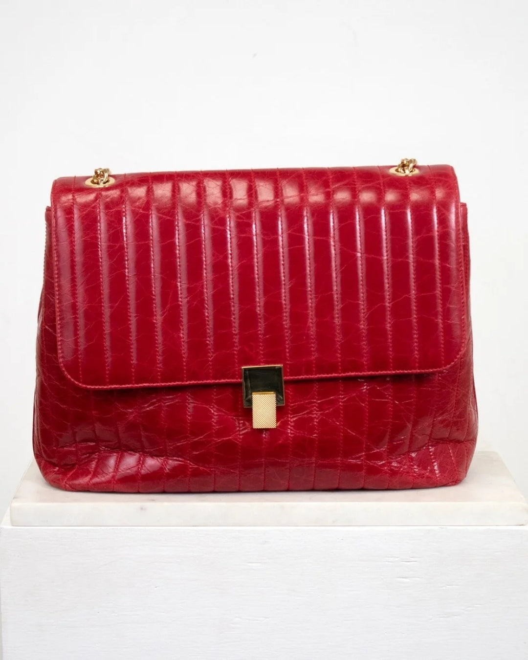 Red textured handbag with gold accents on a white background