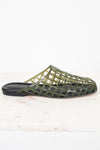 An olive green open-weave mule sandal with a black sole, displayed on a light marble surface against a white background.