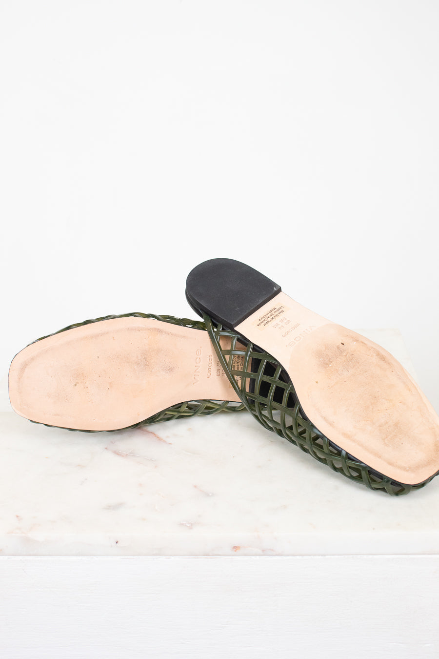 A pair of women's green woven mesh slingback sandals with black heel caps and light beige insoles, displayed on a white marble surface against a white background.