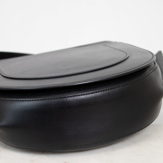 Bottom view of black handbag with gold accents on a white background