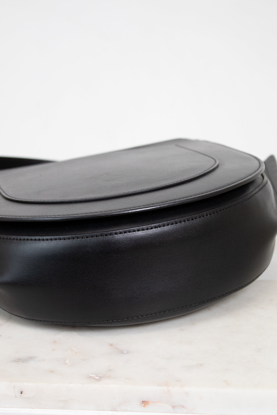 Bottom view of black handbag with gold accents on a white background