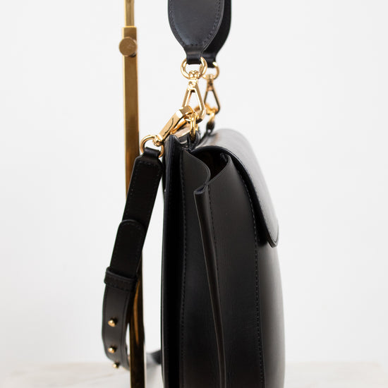 Black handbag with gold accents on a white background