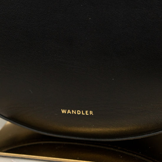 Black leather handbag with 'Wandler' branding on a marble surface