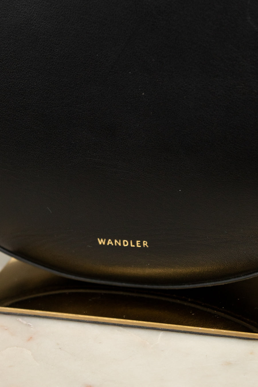 Black leather handbag with 'Wandler' branding on a marble surface