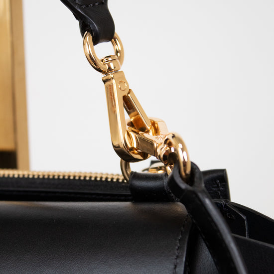 Black handbag with a gold clasp on a white background