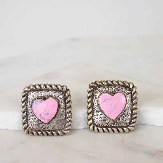 Pair of earrings with pink heart design on a marble surface