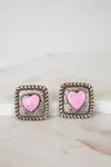 Pair of earrings with pink heart design on a marble surface