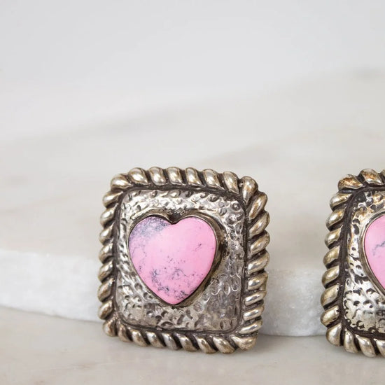 Pair of earrings with pink heart in silver frames on a white background