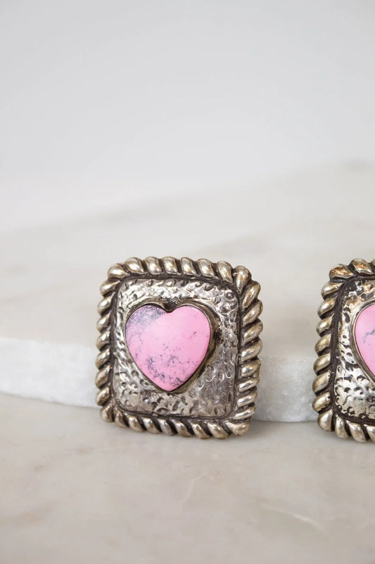 Pair of earrings with pink heart in silver frames on a white background