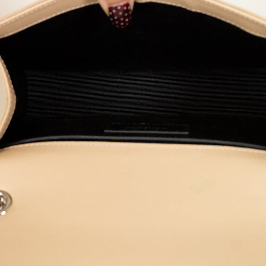 Close-up of a beige handbag with a hand holding it open, showing the interior.