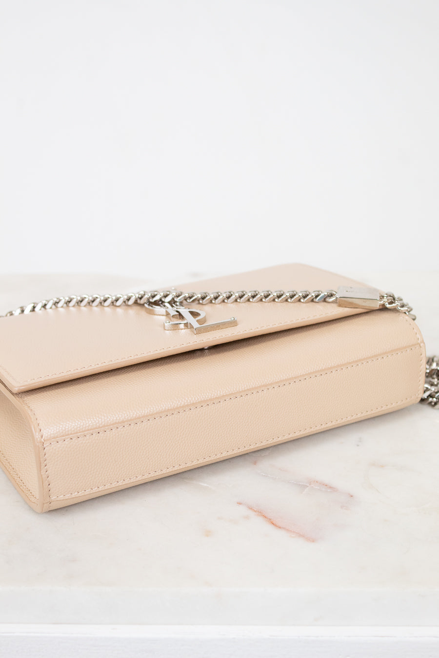 Beige handbag with a chain detail on a marble surface