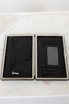 Black wallet with silver trim on a white marble surface