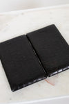 Open black crocodile-patterned wallet on a marble surface