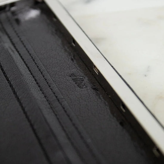 Black leather wallet with a brand logo on a marble surface