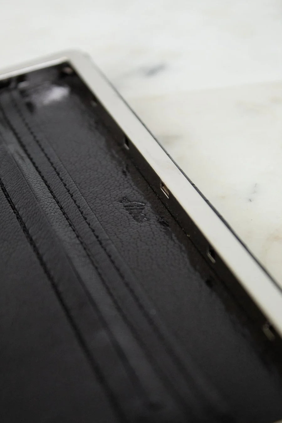Black leather wallet with a brand logo on a marble surface
