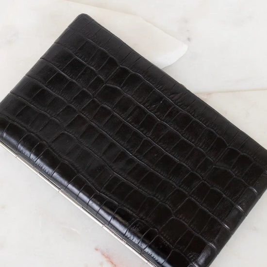 Black crocodile-patterned clutch bag on a light background