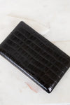Black crocodile-patterned clutch bag on a light background