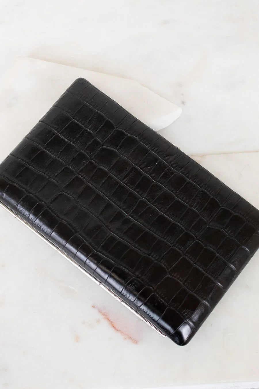 Black crocodile-patterned clutch bag on a light background