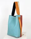 Multicolored tote bag with a blue body, orange strap, and brown handle on a white background