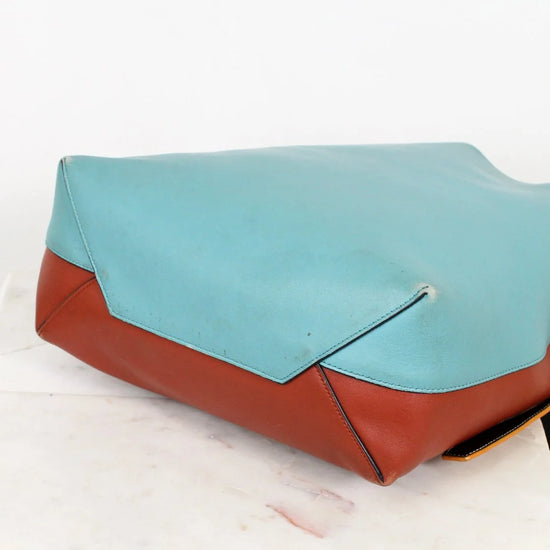 Clutch bag with turquoise top half and brown bottom half on a white background