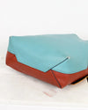 Clutch bag with turquoise top half and brown bottom half on a white background