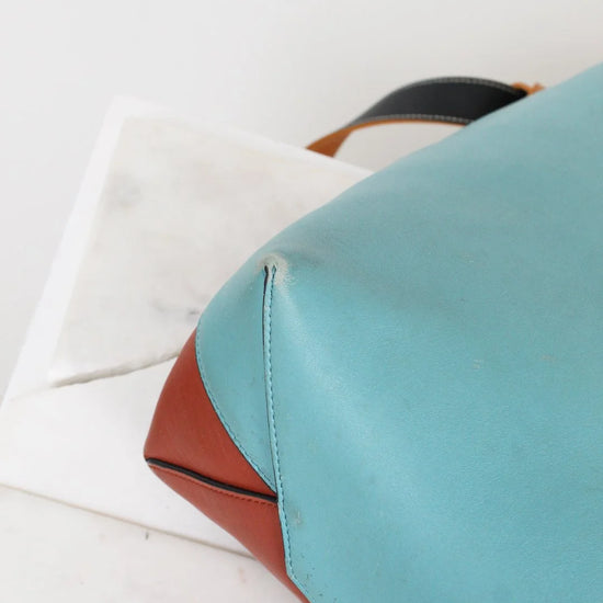 Close-up of a blue and brown leather bag on a white background