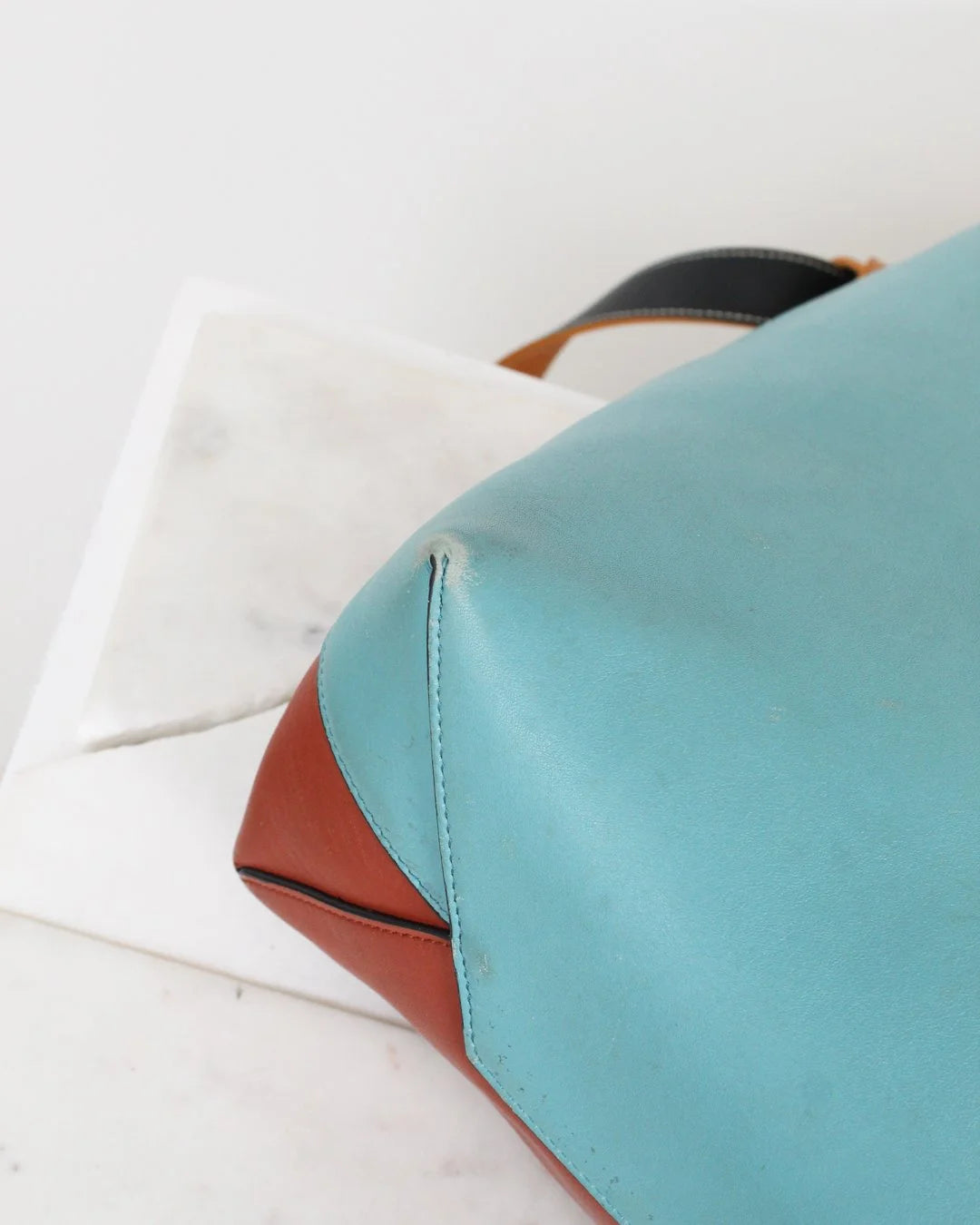 Close-up of a blue and brown leather bag on a white background
