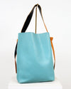 Turquoise tote bag with black and brown straps on a white background