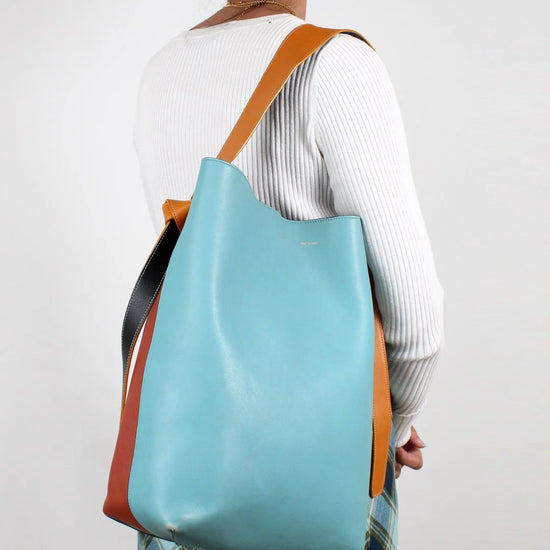 Person wearing a blue and brown tote bag on a plain background