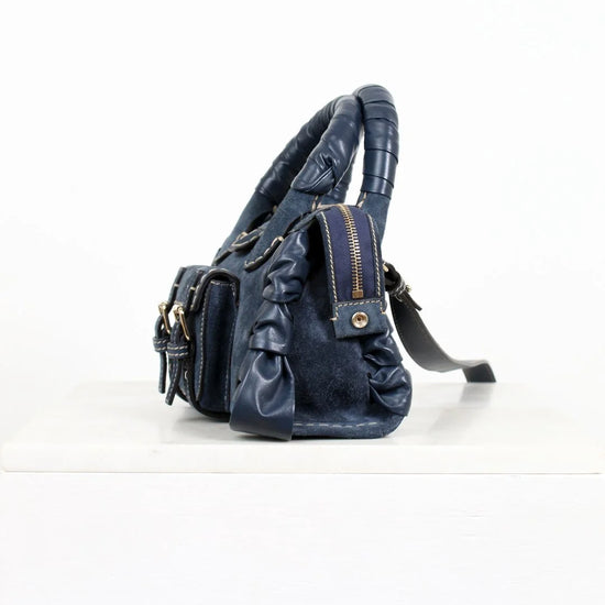 Blue leather handbag with ruched details on a white background