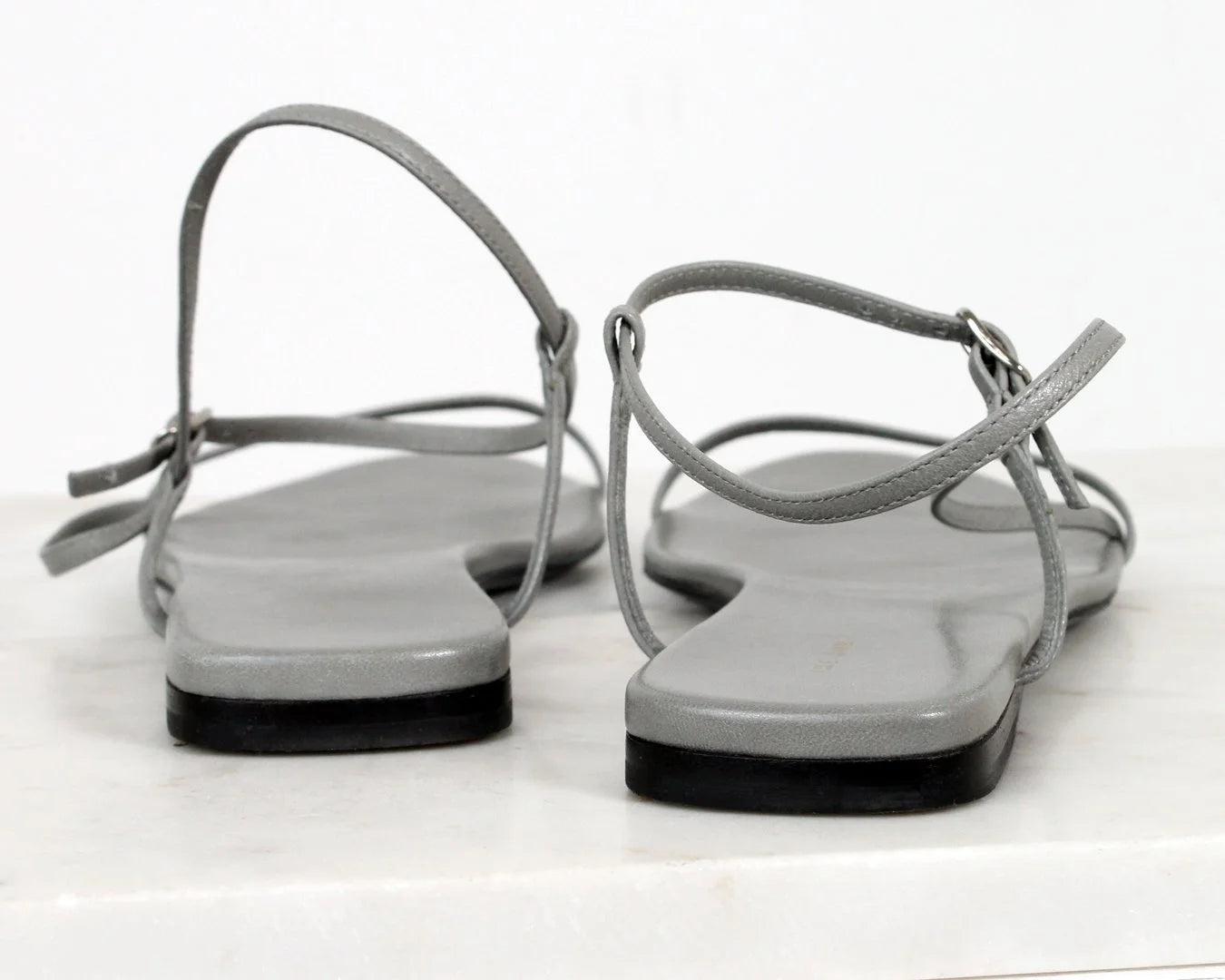 Pair of gray sandals with thin straps on a white background