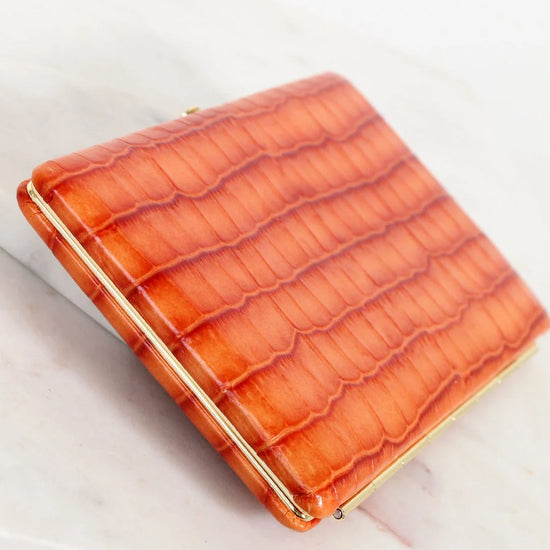 Orange crocodile-patterned wallet on a light background