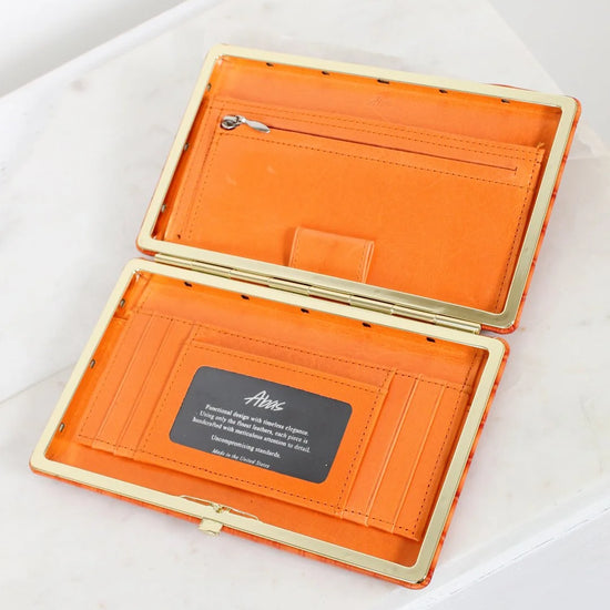 Orange wallet with gold trim on a white surface