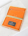 Orange wallet with gold trim on a white surface