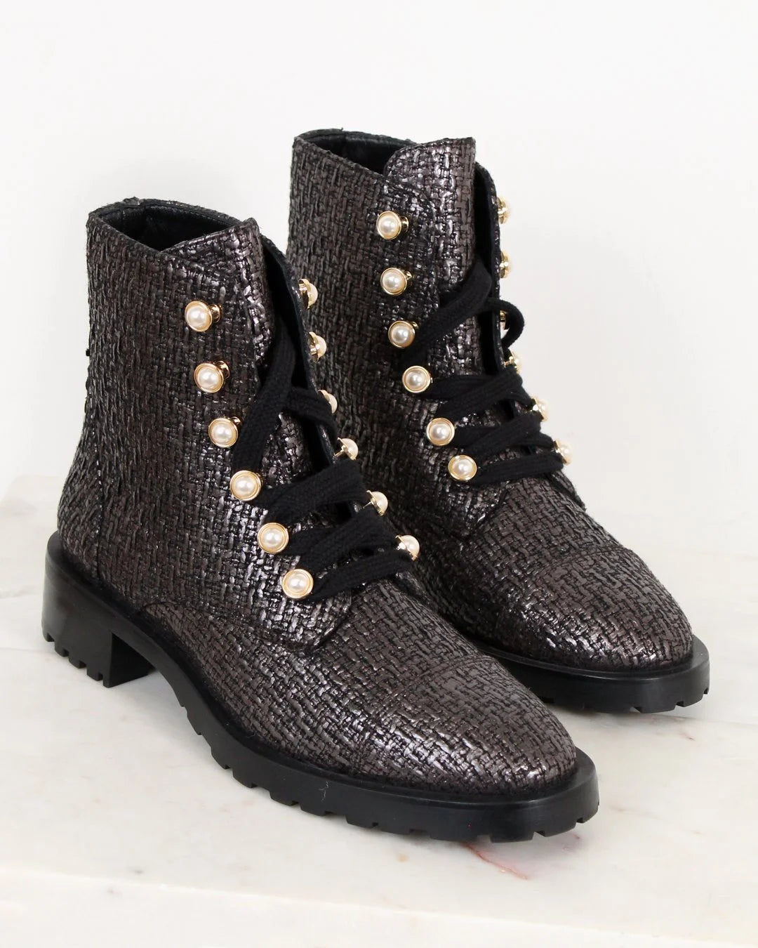 Pair of black and silver textured boots with pearl embellishments on a light background