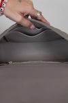 Close-up of a person holding a gray handbag with a zipper.