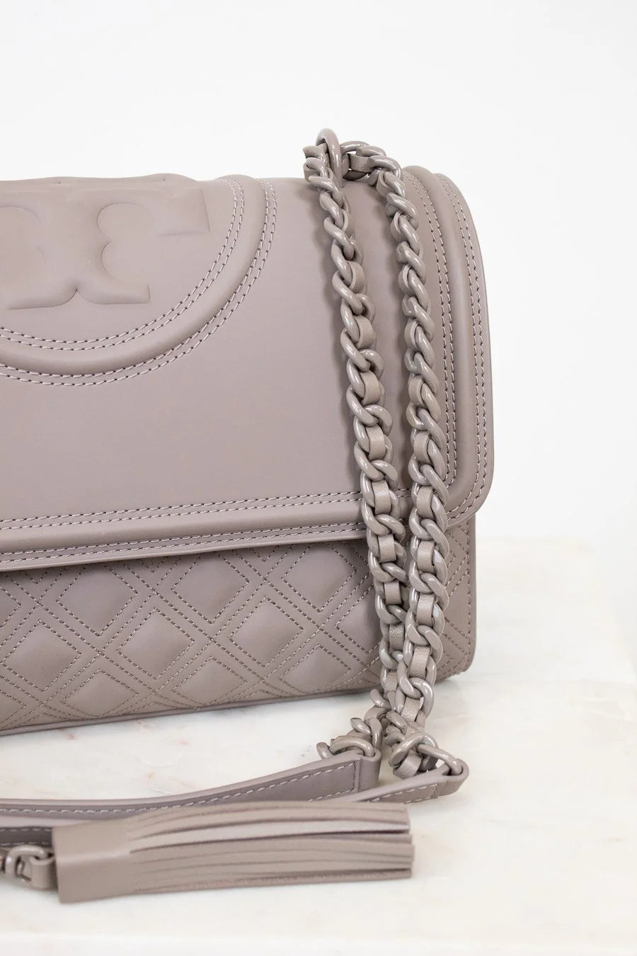 Gray quilted handbag with a chain strap on a white background