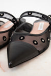 Black pointed-toe shoes with mesh design and decorative elements on a light background