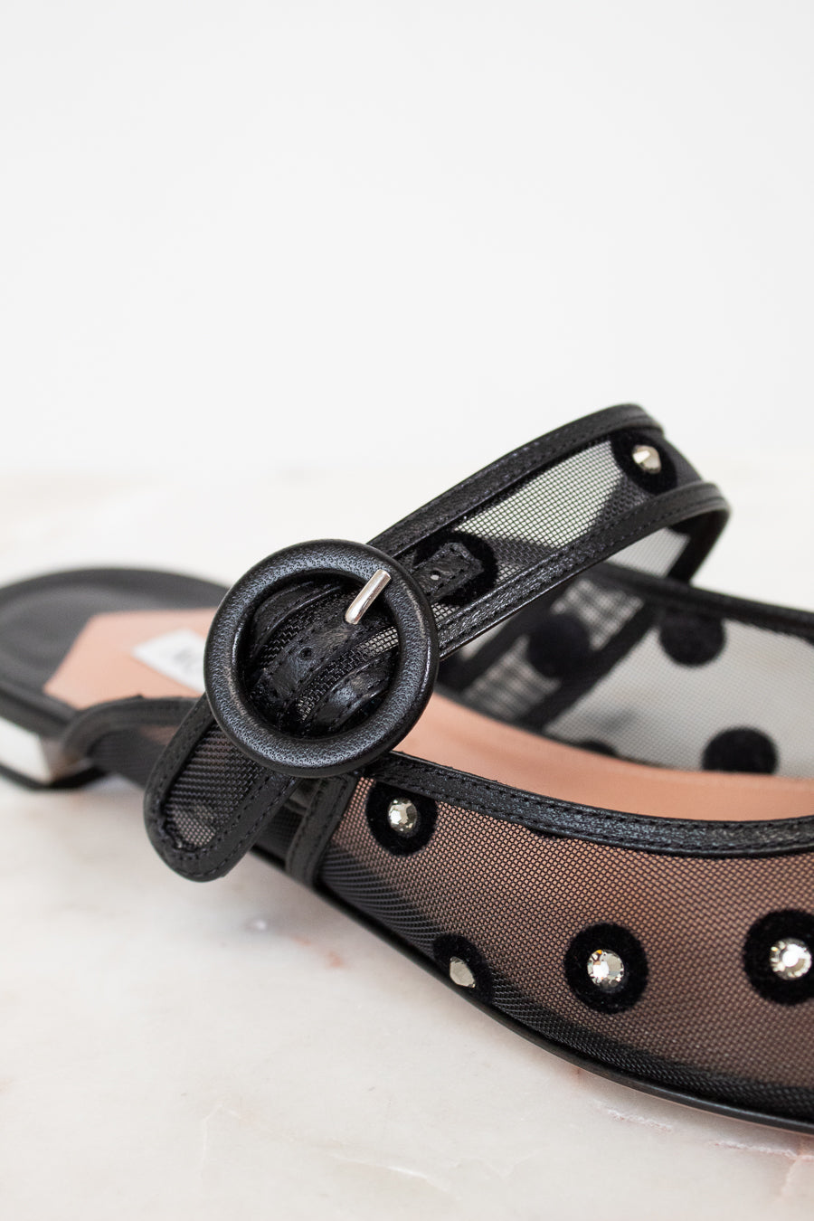 Black strappy sandal with mesh overlay on a light background